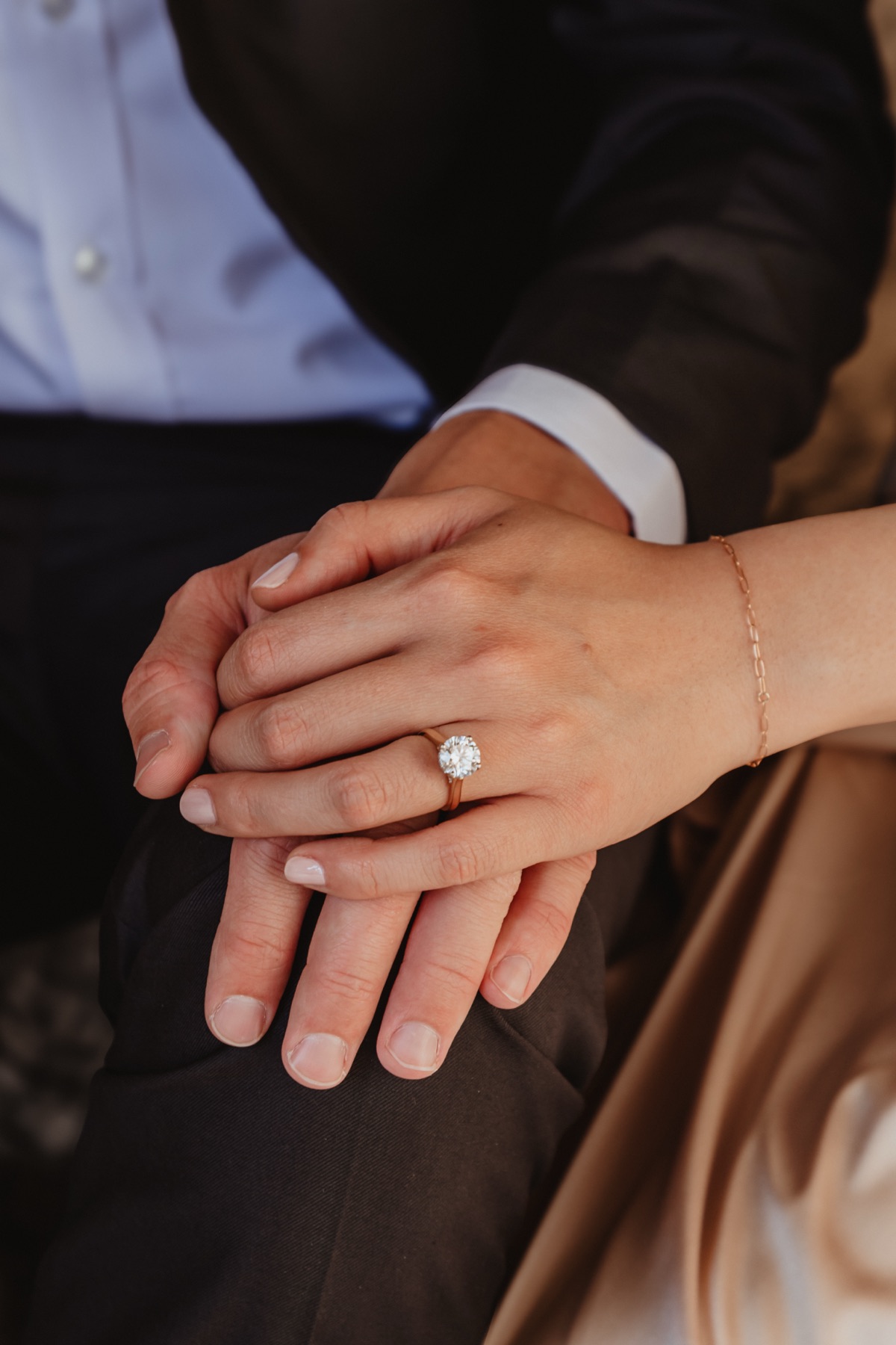 Their hands together, her engagement ring in view